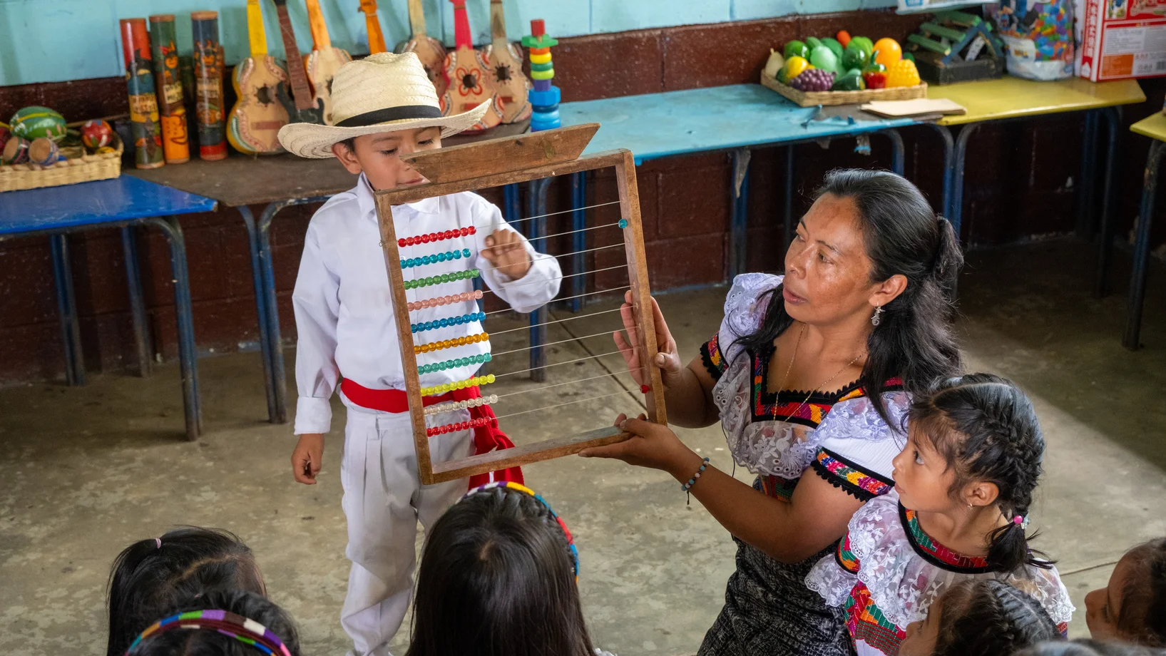 Kindergartenlehrperson mit Kindern im Unterricht, mit einem Rechenschieber